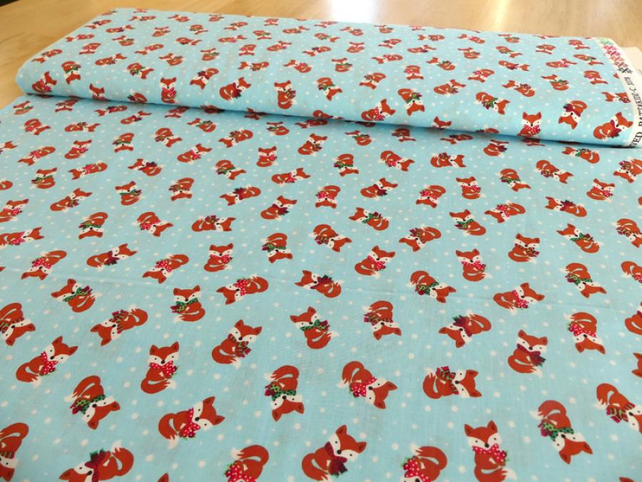Preview: Patchworkstoff mit Füchsen mit Schal und Schneeflocken auf hellblau. Von Timeless Treasures.