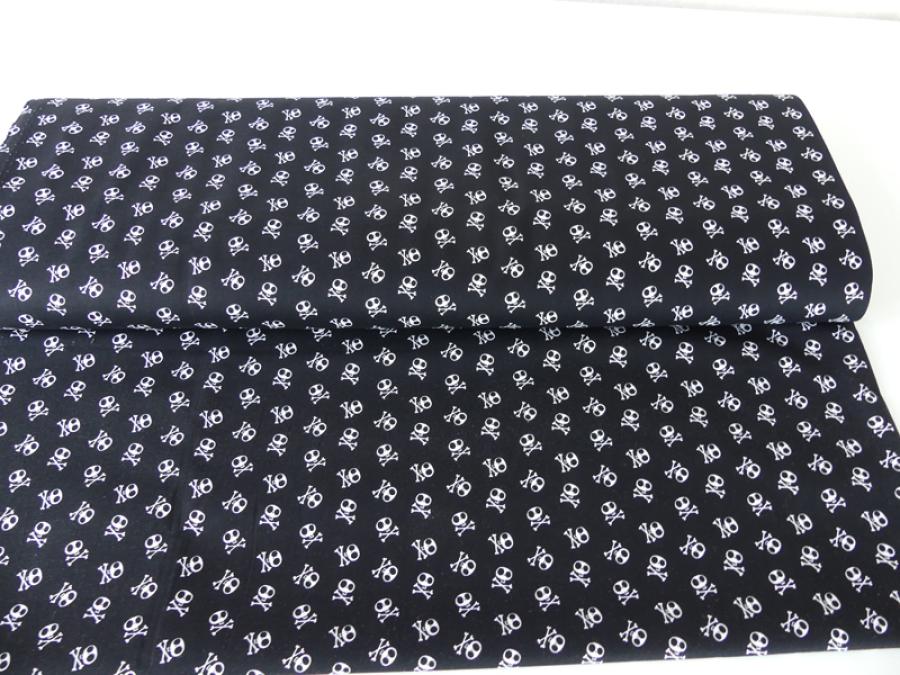 Patchworkstoff in schwarz mit vielen, kleinen, weißen Totenköpfen von Riley Blake.
