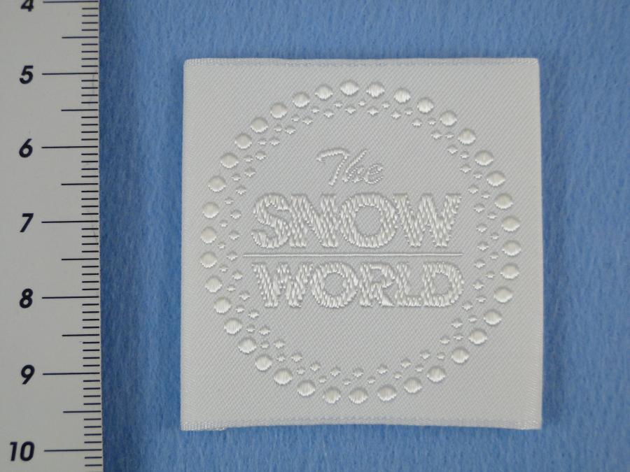 Preview: Etikett zum Aufnähen Snow-World strahlend weiß. Detailansicht mit Maß.