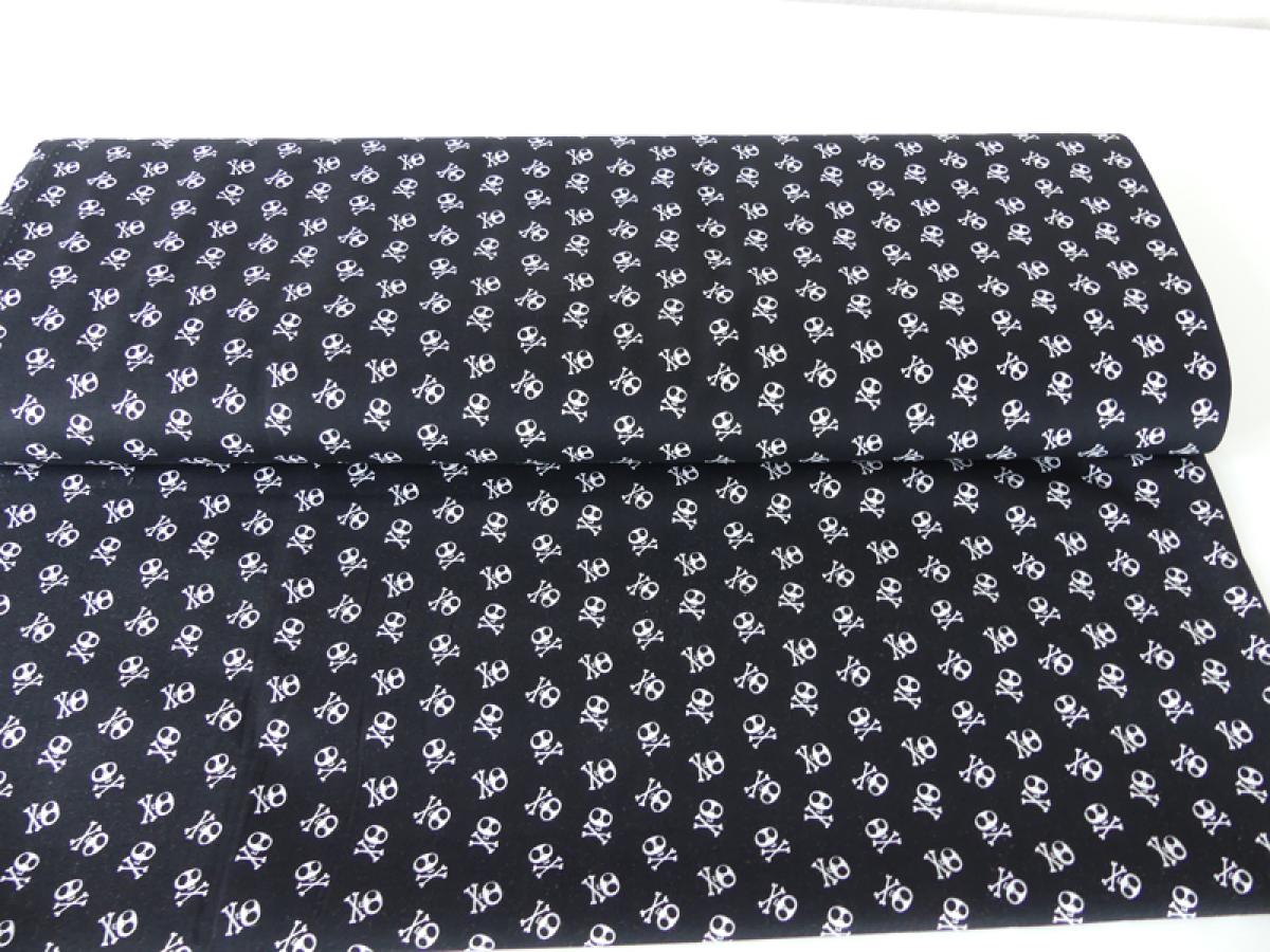 Patchworkstoff in schwarz mit vielen, kleinen, weißen Totenköpfen von Riley Blake.